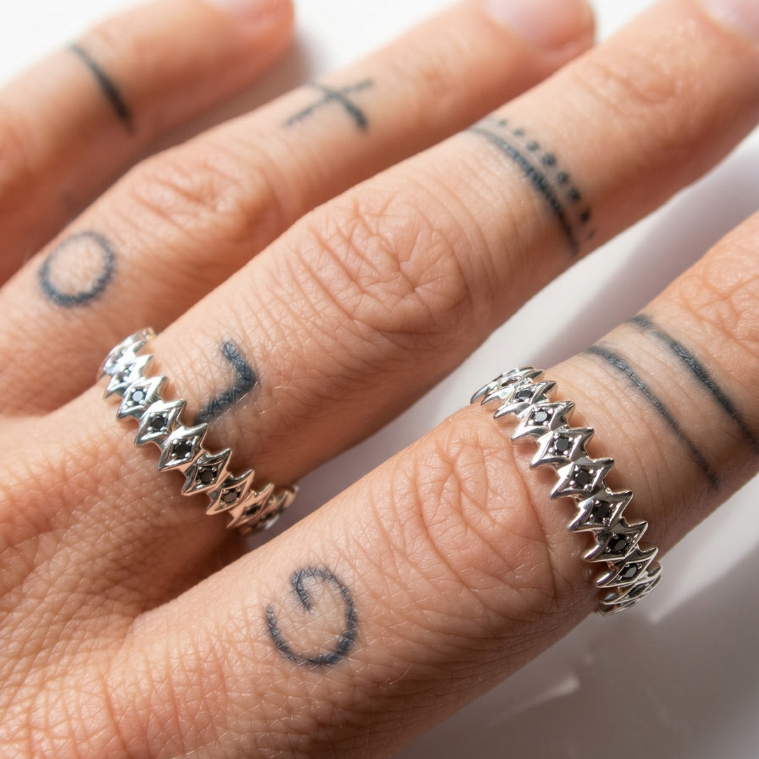 White gold ring with star designs with black diamonds
on a white background