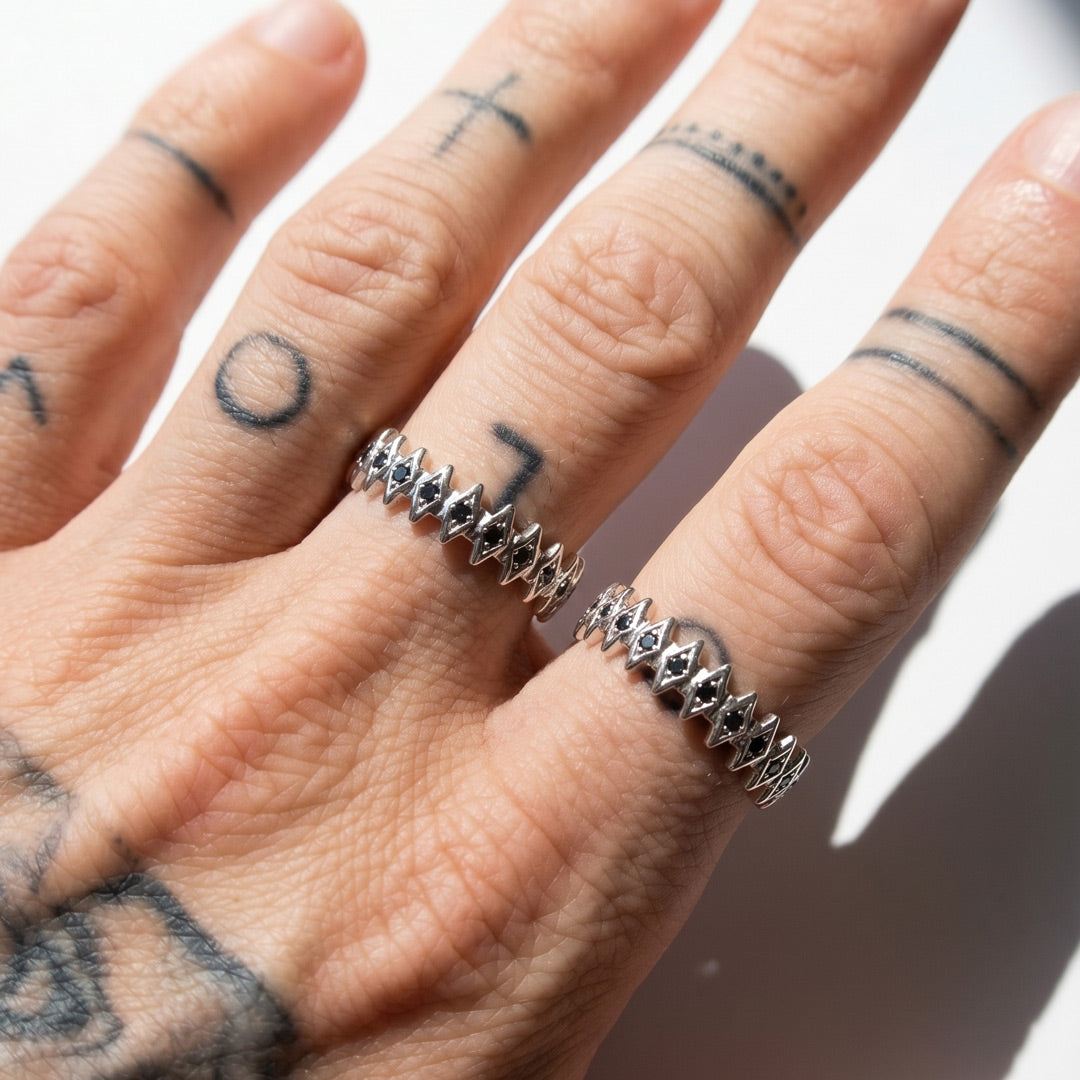A hand wearing two white gold rings with a blurred background