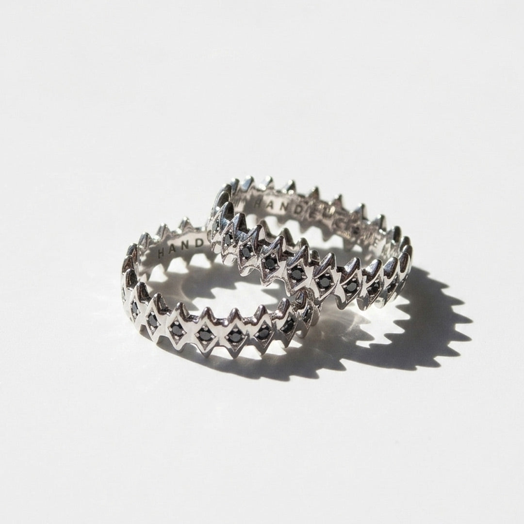 White gold rings with a star-like design and black diamonds on a white background