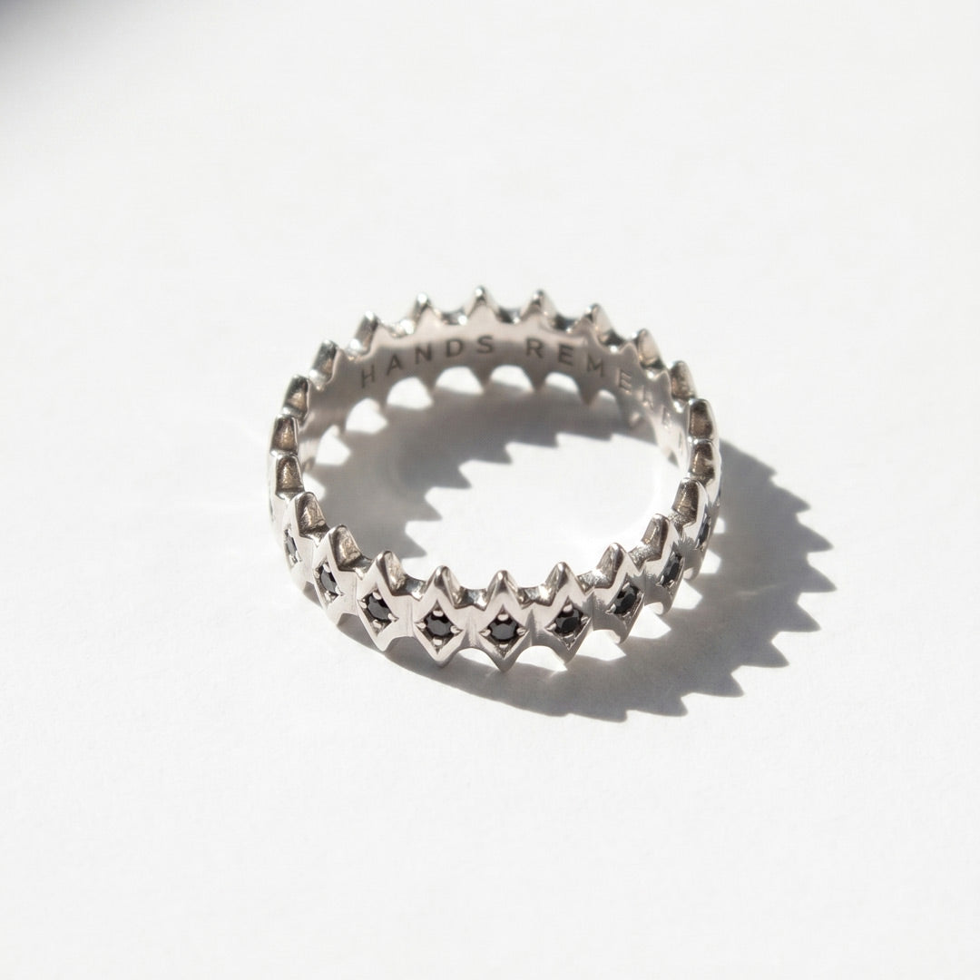 White gold ring with star designs with black diamonds
 on a white background