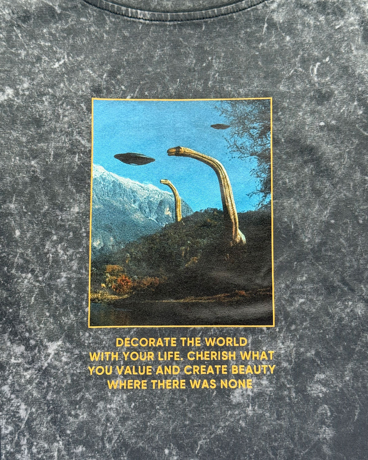 T-shirt with a graphic design of a UFO and alien hand reaching towards a mountain, with text on a textured gray background.