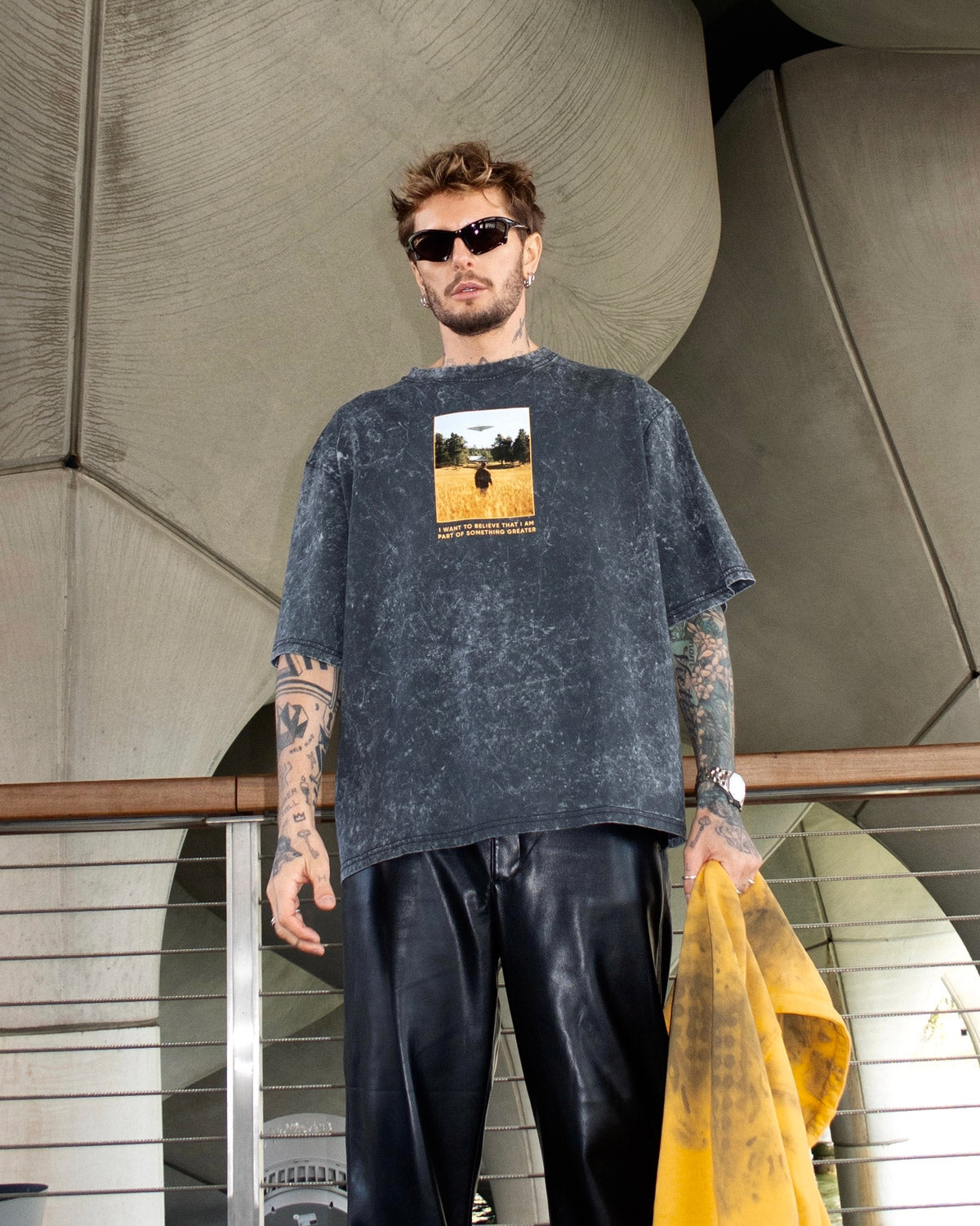 Oscar Renkel is wearing a graphic t-shirt featuring a photo of a person standing in a field against a UFO