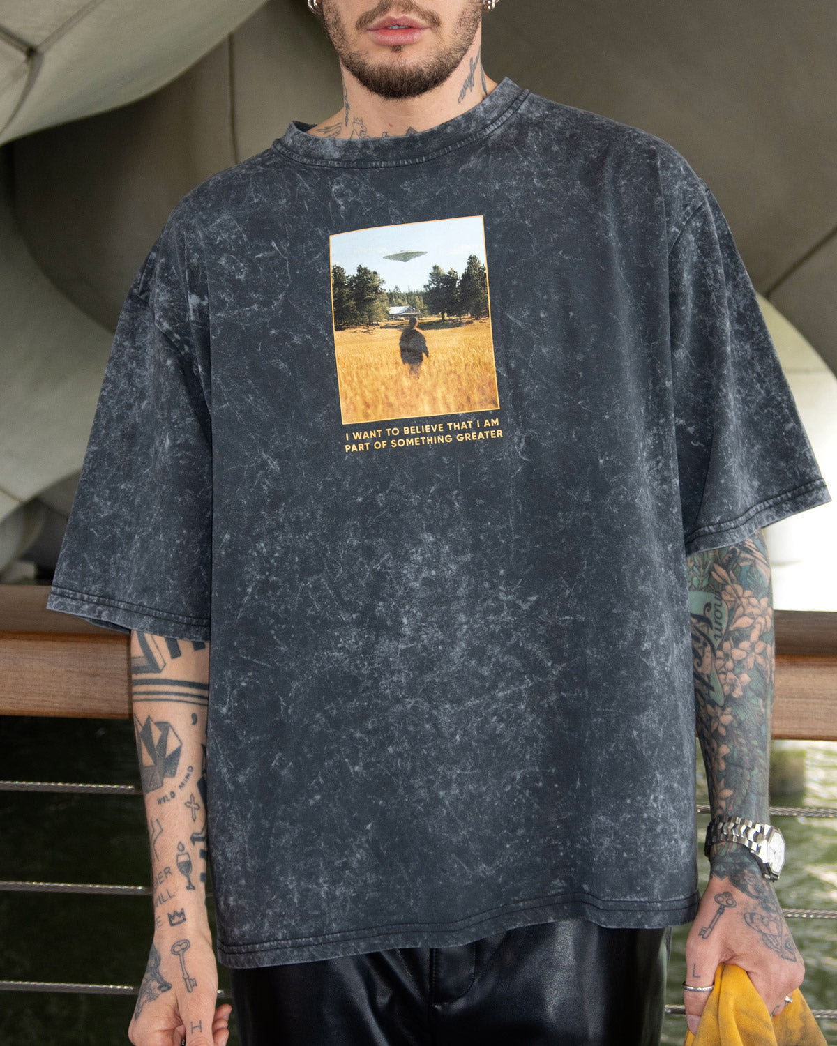 Oscar Renkel is wearing a graphic t-shirt featuring a photo of a person standing in a field against a UFO