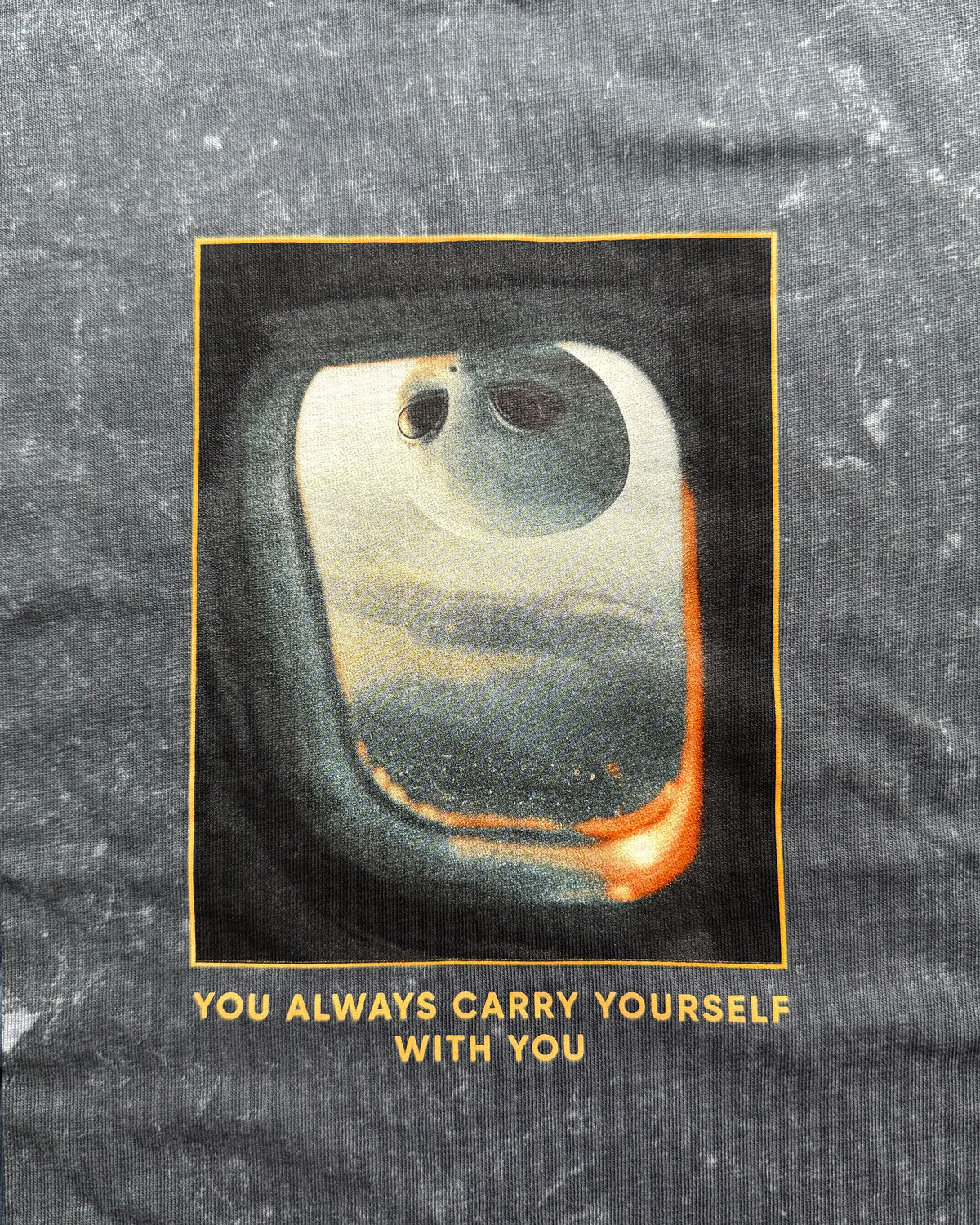 T-shirt with a graphic of a face in space and text 'You always carry yourself with you' on a textured black background.