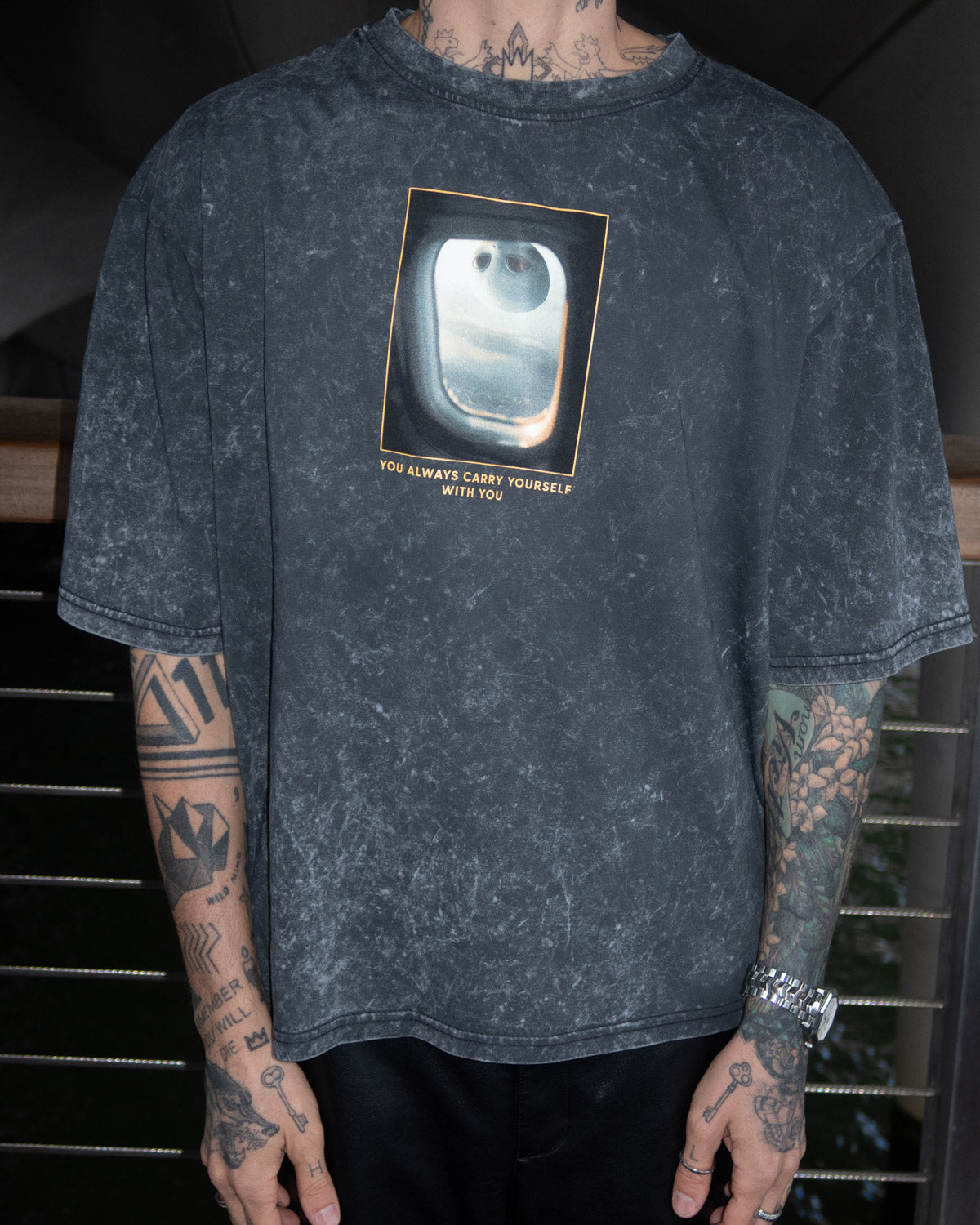 Person wearing a dark gray t-shirt with a graphic design and text.