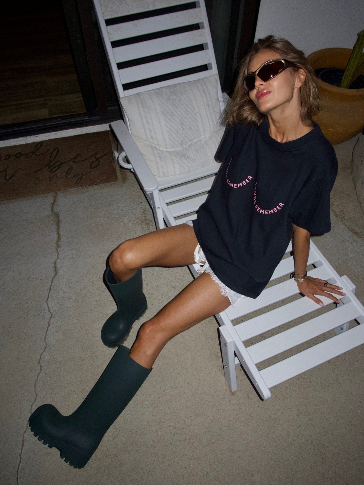 Black T-shirt with the “Hands Remember” graphic shaped across the chest, relaxed seated view.