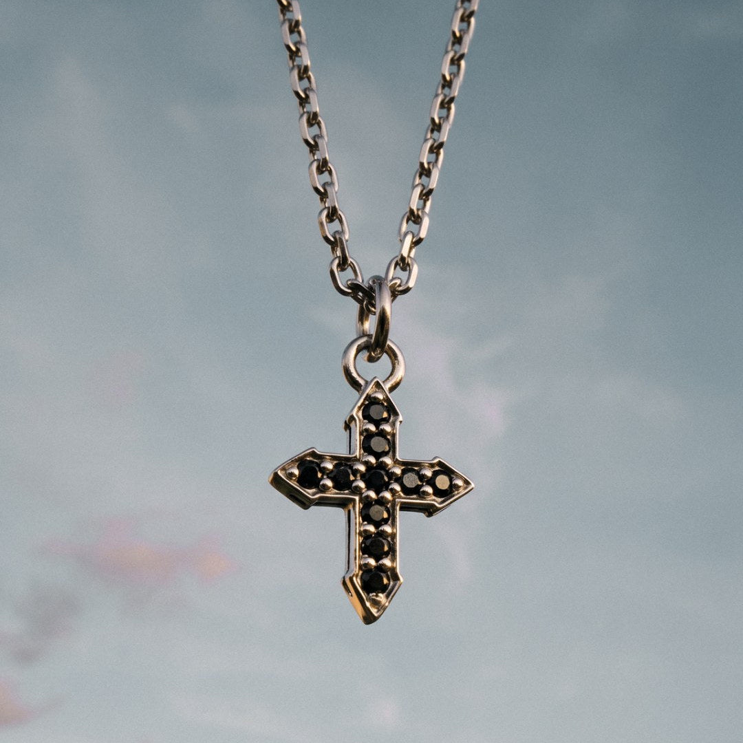 Glow cross pendant with black spinel on a sterling silver chain, front view.