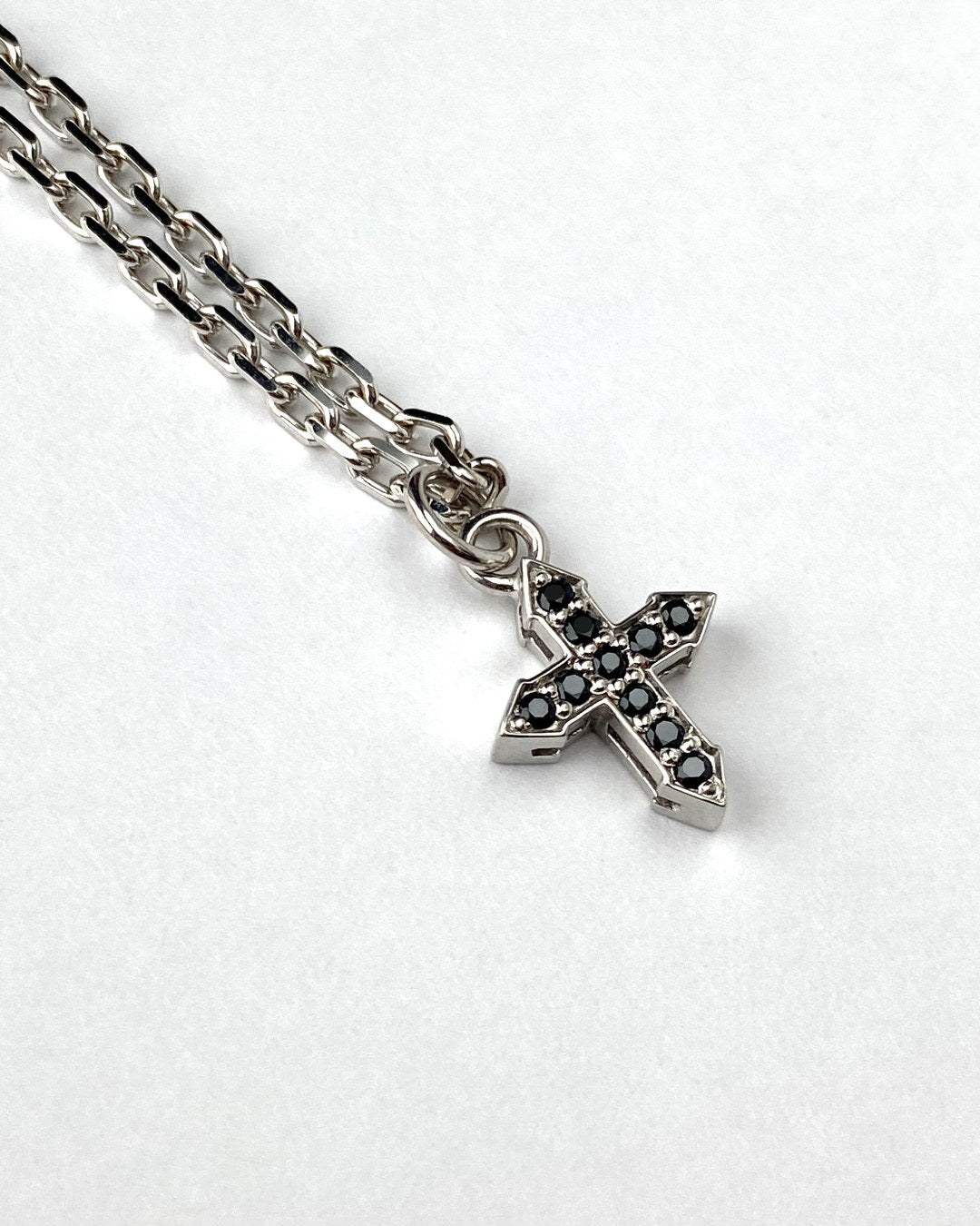 Glow cross pendant with black spinel on a sterling silver chain, close-up product view.