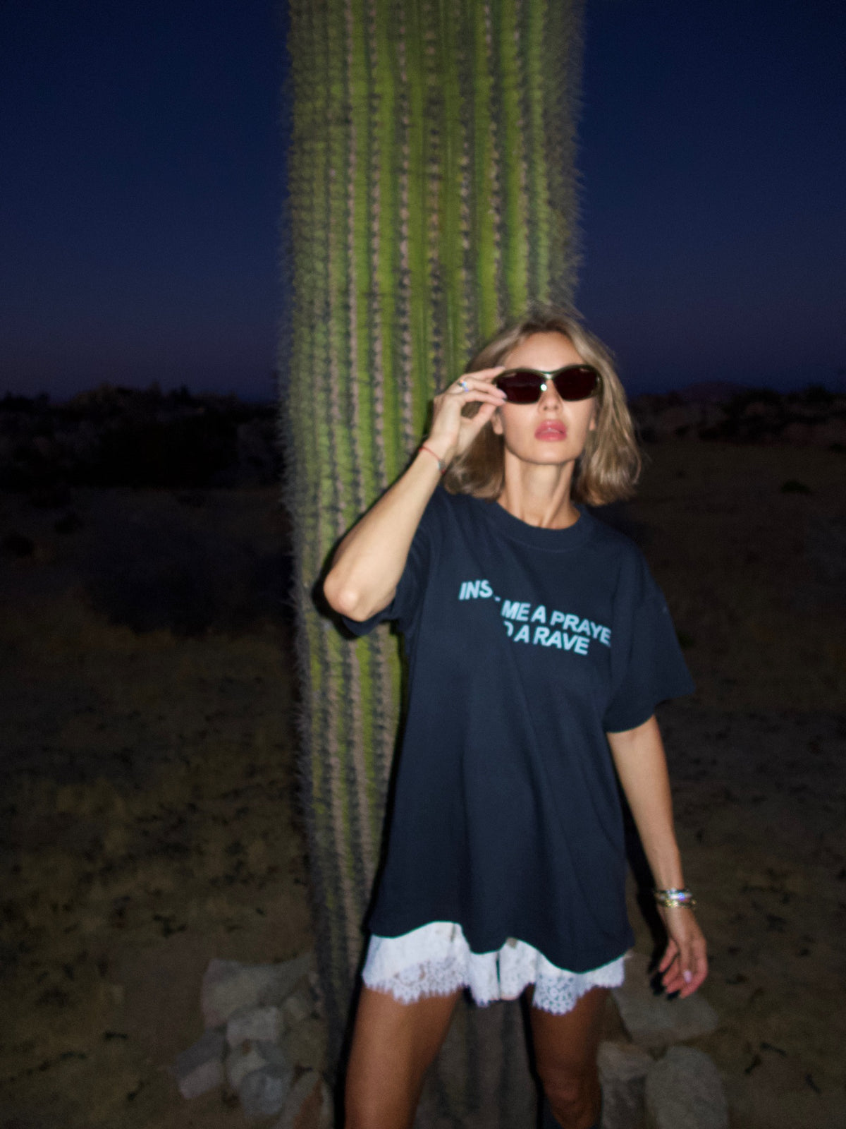 Black T-shirt with the “Inside Me a Prayer and a Rave” print, full-length view in front of a tall cactus