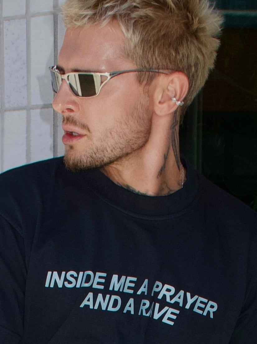 Black T-shirt with the “Inside Me a Prayer and a Rave” print, close-up portrait view